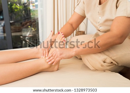 Professional Asian Therapist twist and massage spa on foot of customer to release stress relax muscle pain or injury. Physiotherapist pressing hard fingers thumb on specific spots of female palm feets