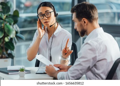professional asian translator working online with headset while having meeting with businessman