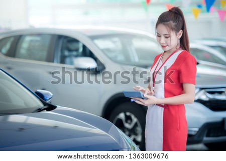 Professional Asian woman female salesperson at car dealership Use the calculator to calculate the car interest price.,Salesperson selling cars