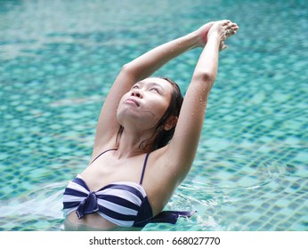 professional asian woman practice yoga sequence warrior 1 pose (Virabhadrasana I) close up in swimming pool, aqua yoga blue water