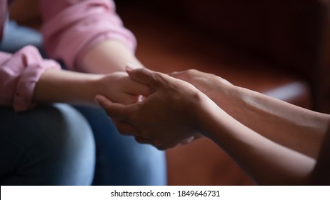 Professional assistance. Close up of biracial female psychologist therapist hands holding palms of millennial woman or teenage girl patient client talking consulting helping accept difficult situation