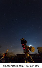 Professional Astrophotography Telescope Equipped With Guider Scope And Astro Camera Is Taking Pictures Of Night Sky, Equipment Lit Only By LED Lights And Dim Lights Of Stars