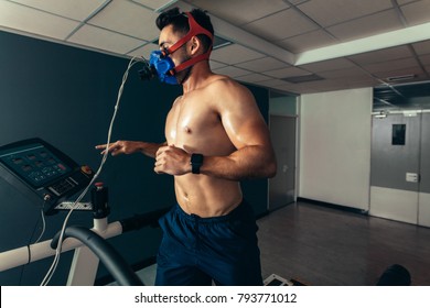 Professional Athlete Monitoring His Performance In Sports Science Lab. Muscular Man With Face Mask Running On Treadmill In Gym.