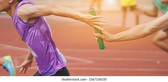 Professional Athlete passing a baton to the partner against race on racetrack.selective focus. - Shutterstock ID 1567136533