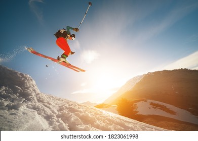 Professional athlete young male skier with a backpack and in a ski mask makes a trick in flight after jumping from a kicker on the background of a sunset