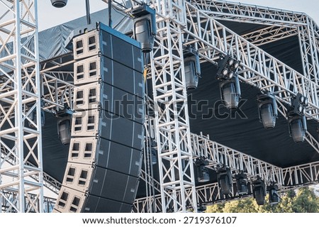 Professional audio line array speakers and moving head light fixtures hanging on a metal truss structure for an outdoor event or concert