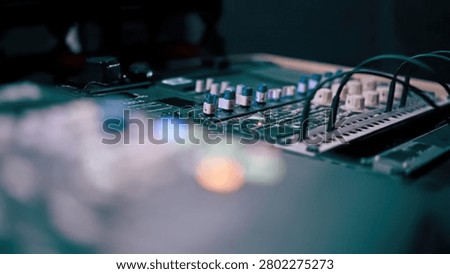 A professional audio mixer with knobs and sliders in a music studio setting.