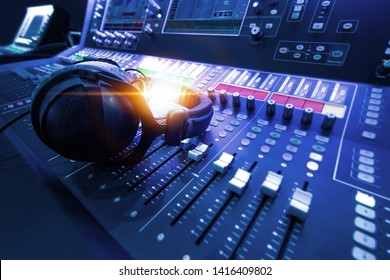 Professional audio studio sound mixer console board panel with recording , faders and adjusting knobs,TV equipment. Blue tone and close-up image with flare light effect.