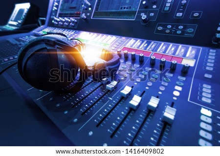 Professional audio studio sound mixer console board panel with recording , faders and adjusting knobs,TV equipment. Blue tone and close-up image with flare light effect.