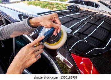 Professional Auto Detailer Hand Holding Air Random Orbital Sander Or Dual Action Polisher While Waxing Paint Surface Of Shiny Black Sedan. Car Detailing, Car Wash, And Paint Sealant Concept.