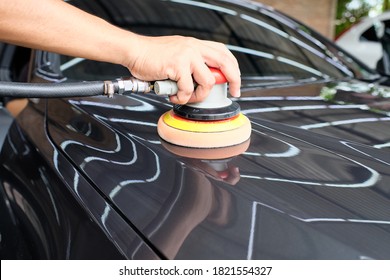 Professional Auto Detailer Hand Holding Air Random Orbital Sander Or Dual Action Polisher While Waxing Paint Surface Of Shiny Black Paint. Car Detail, Car Wash, And Paint Protection Concept. 