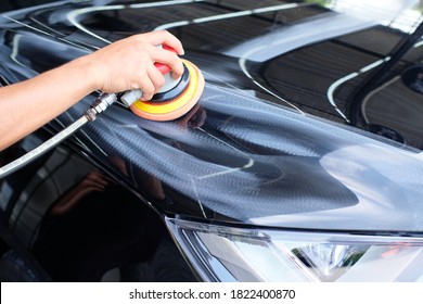 Professional Auto Detailer Hand Holding Air Random Orbital Sander Or Dual Action Polisher While Waxing Paint Surface Of Shiny Black Paint. Car Detail, Car Wash, And Paint Sealant Concept.  