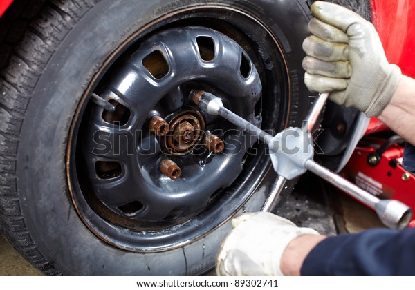 Professional auto mechanic changing a tire in\
auto repair shop.\
Garage.