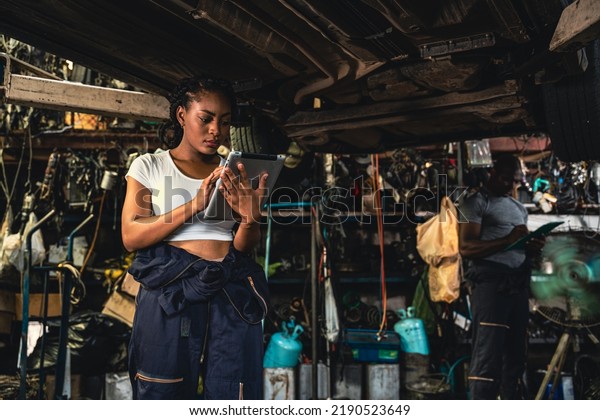 Professional\
auto mechanic checking cars after completing the list of repairs\
using a tablet to record data in the\
garage.