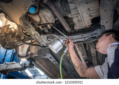 Professional auto mechanic working on the undercarriage of a car diligence attention inspection examination annual checkup safety insurance professionalism occupation transportation vehicle concept - Powered by Shutterstock