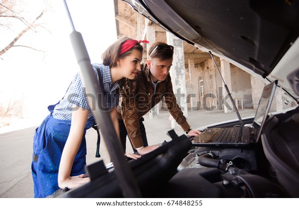 Professional auto woman mechanic and man repair
auto outdoors