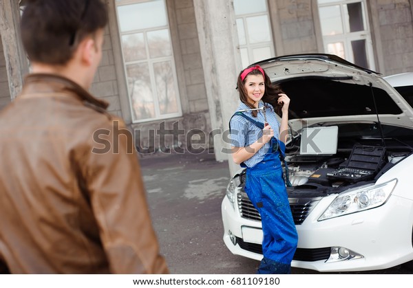 Professional auto woman mechanic and man repair\
auto outdoors