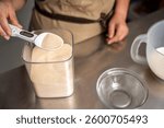 Professional baker using a digital spoon scale to accurately measure yeast, ensuring precise ingredient proportions for delicious pastries