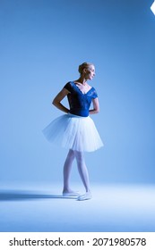 professional ballerina on pointe, dancing in classical positions, light blue background, ballerina wearing white tutu in studio doing classical ballet positions