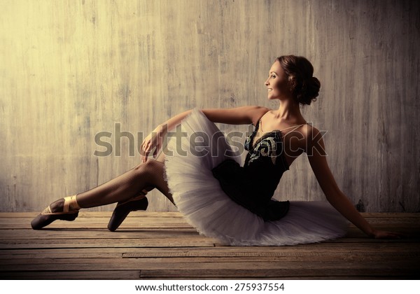 Professional ballet dancer posing at studio over\
grunge background. Art\
concept.