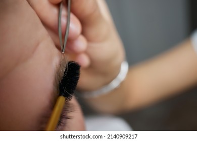 Professional barber doing threading procedure and correcting shape of eyebrows to young male client with tweezer in barber shop. Barber at work. Brow care concept. Plucking brows. - Shutterstock ID 2140909217