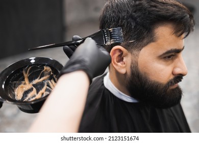 Professional Barber Dying Male Client Hair In Barbershop. Hairdresser Applies Dye To The Client's Hair With A Brush