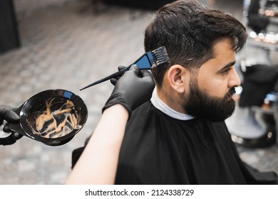 Professional barber dying male client hair in barbershop. Hairdresser applies dye to the client's hair with a brush - Powered by Shutterstock