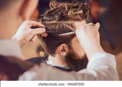 Professional barber styling hair of his client