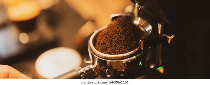 A professional barista. Concept of modern warm coffee shop and Preparing process of coffee. Close up of a hand holding a filter holder with ground coffee in a Cafe or coffee shop. - Powered by Shutterstock