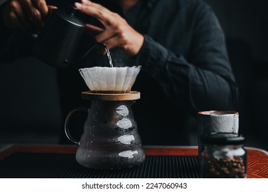 Professional barista making filtered drip coffee in coffee shop. Close up of hands barista brewing a drip hot espresso, pour over coffee with hot water and filter paper in cafe. - Shutterstock ID 2247060943