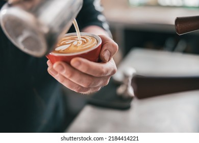 Professional Barista pouring milk in glass of fresh made coffee for making latte or cappuccino