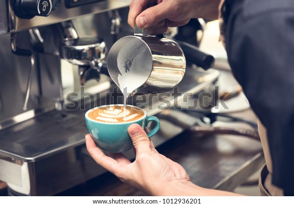コーヒーカップに蒸した牛乳を注ぐプロのバリスタで 美しいラテアートロゼッタ柄を作る の写真素材 今すぐ編集 1012936201