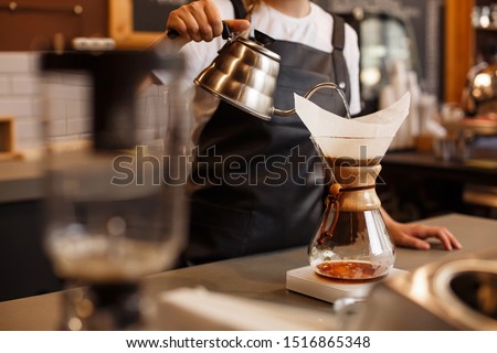 Professional barista preparing coffee using chemex pour over coffee maker and drip kettle. Alternative ways of brewing coffee. Coffee shop concept.