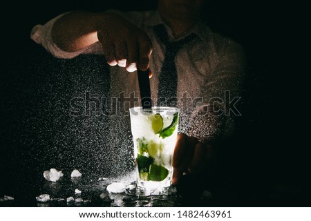 Professional bartender making Mojito cocktail and splashing it out