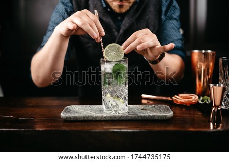 Similar – Image, Stock Photo Detail of a bartender opening a bottle of beer using a bottle opener at a bar counter.