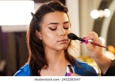 Professional beautician applying makeup on beautiful young woman's face. Professional make up studio work with gorgeous female model. - Powered by Shutterstock