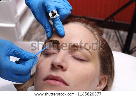Professional Beautician Asian woman applying Tottoo, Brow Microblading to caucasian customer eyebrows to make permanent color makeup or tattooing line look real in beauty salon, copy space text logo
