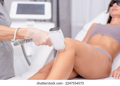 Professional beautician removes hair on beautiful female legs using a laser. hair removal on the legs, laser procedure at clinic - Shutterstock ID 2247554573