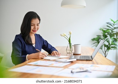 Professional And Beautiful Asian Businesswoman Woking On Her Business Assignment At Her Office Desk.