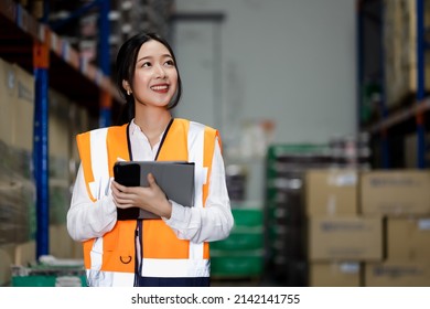 Professional Beautiful Asian Woman Worker Checks Stock And Inventory With Digital Tablet Computer In The Retail Warehouse Full Of Shelves With Goods. Working In Logistics, Distribution Center.