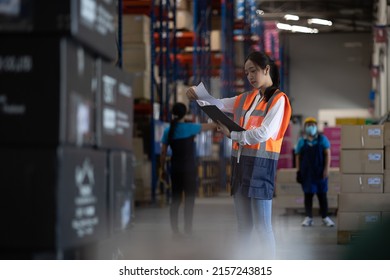 Professional beautiful asian woman worker checks stock and inventory with holding clipboard in the retail warehouse full of shelves with goods. Working in logistics, Distribution center. - Powered by Shutterstock