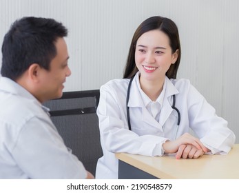 Professional Beautiful Young Asian Female Doctor Talking With A Man Patient About His Pain And Symptom While They Put On A Face Mask  At The Examination Room In Hospital.