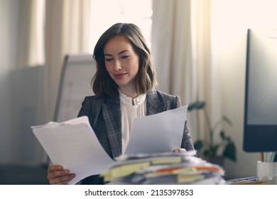 Professional And Beautiful Young Business Woman And Female Editor Reviewing Some Paperwork At Her Office. Looking Happy And Satisfied, And Enjoy Working. 