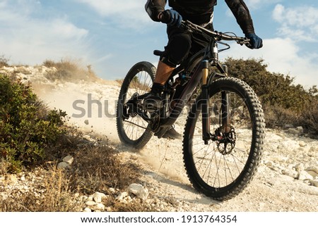 Professional bike rider fully equipped with protective gear during downhill ride on his bicycle