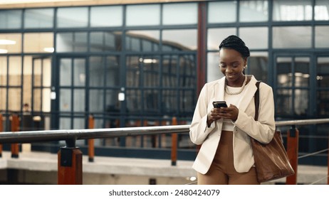 Professional Black Woman Using Smartphone in Modern Industrial Business Setting - Powered by Shutterstock