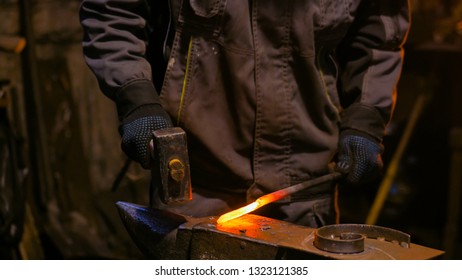 Professional Blacksmith Forging Molten Metal On Anvil At Smithy, Workshop. Handmade, Craftsmanship And Blacksmithing Concept