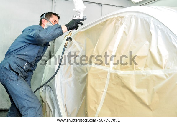 Professional body\
shop worker painting white\
car.