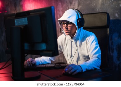 Professional Boy Gamer Plays In Video Game On A ESports Tournament Or In Internet Cafe. He Wears Headphones And Speaks Commands Into Microphone.