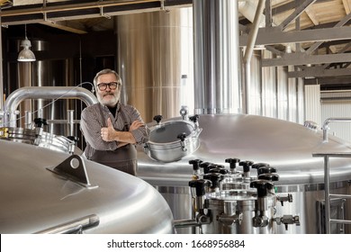 Professional brewer on his own craft alcohol production. Specialist, senior man in workwear posing confident. Concept of open business, eco product, craft brewery, factory, manufactory, start up. - Powered by Shutterstock