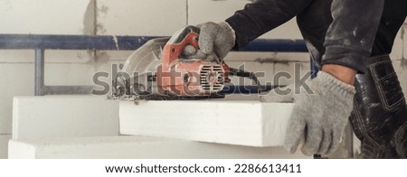 Professional Bricklayer using electric saw cutting lightweight brick for resize block to build a wall. Material lightweight brick.